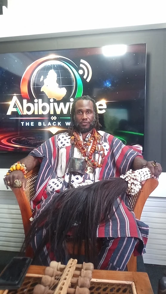 Ɔbenfo Ọbádélé Kambon in traditional attire in front of the Abibiwiase backdrop